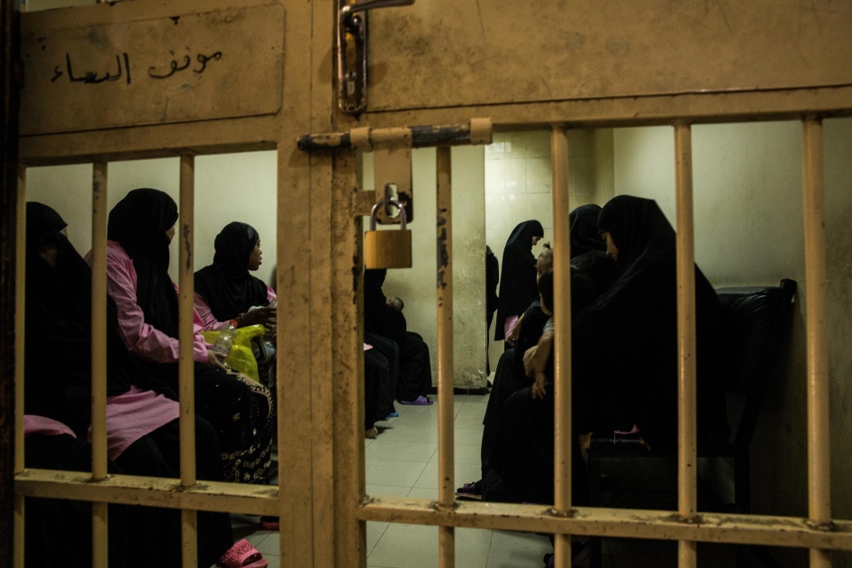Women and children wait in a holding cell